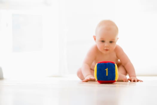 Baby sitting indoors with block