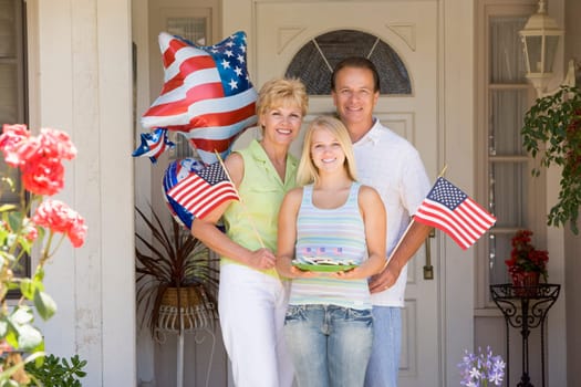 Family at front door on fourth of July with flags and cookies smiling