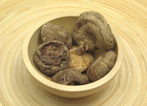 Wooden bowl with shiitake on bamboo plate
