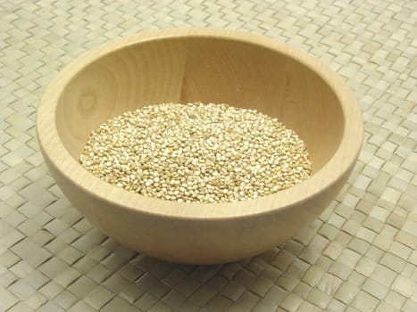 Wooden bowl with quinoa on rattan base