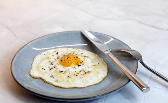 Breakfast served on the kitchen table with a fried egg on a plate. High quality photo