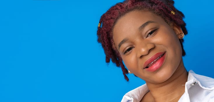 Portrait of nice attractive african american woman against blue background, close up
