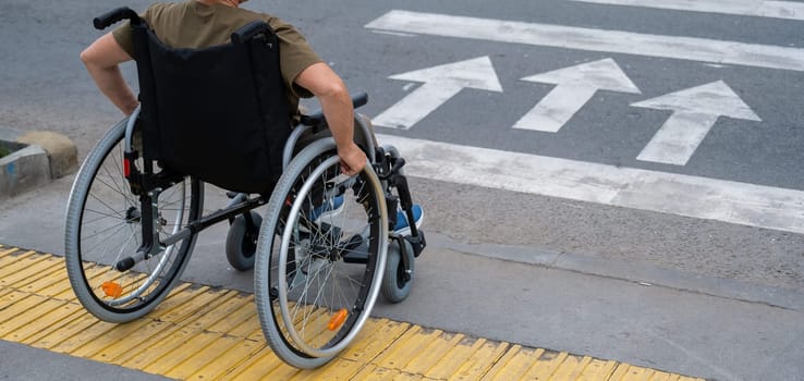 An elderly woman in a wheelchair is about to cross the road at a pedestrian crossing