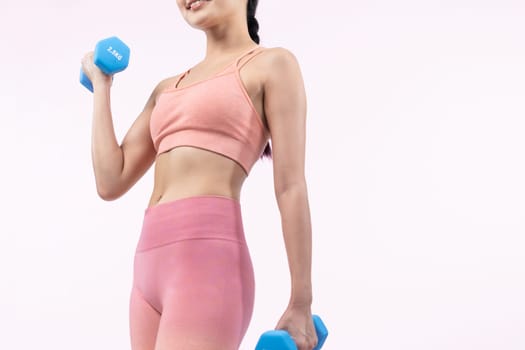 Vigorous energetic woman doing dumbbell weight lifting exercise on isolated background. Young athletic asian woman strength and endurance training session as body workout routine.