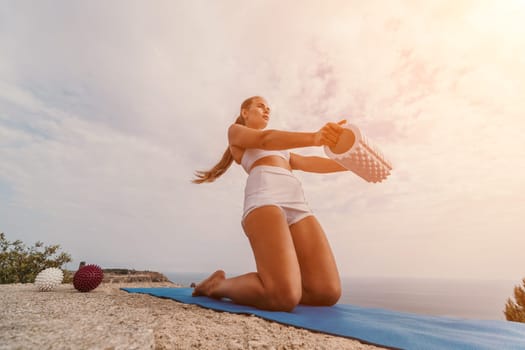 Woman sea pilates. Sporty, middle-aged woman practicing pilates in park near the sea. trains on a yoga mat and exudes a happy and active demeanor, promoting the idea of a healthy lifestyle through exercise and meditation.