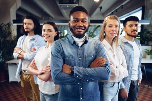 Group portrait of five diverse young colleagues standing in a row in modern office