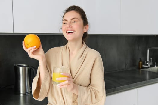 young pretty woman cooking at home, morning kitchen, healthy food, drinking orange juice.