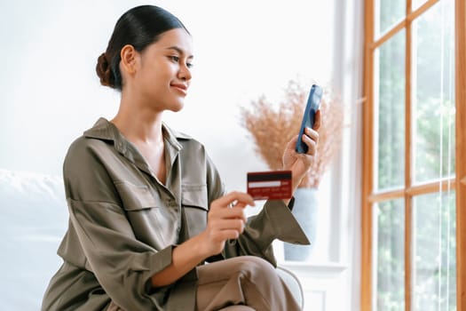 Young happy Asian woman buy product by online shopping at home while ordering items from the internet with credit card online payment protected by uttermost cyber security from online store platform