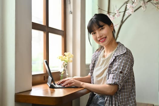 Portrait of young Asian woman hands typing on keyboard, working online, searching in internet. People and technology concept.