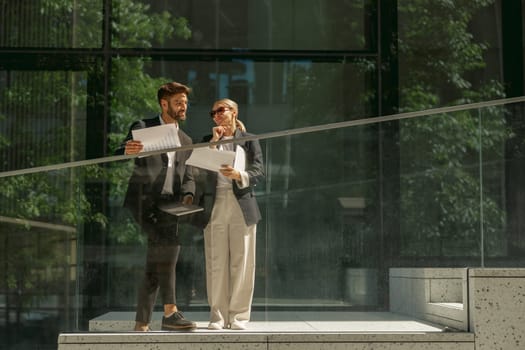 Business analysts working with documents while standing on background of modern office building