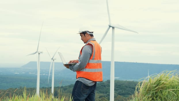 Engineer working on a wind farm atop a hill or mountain in the rural. Progressive ideal for the future production of renewable, sustainable energy. Energy generation from wind turbine.