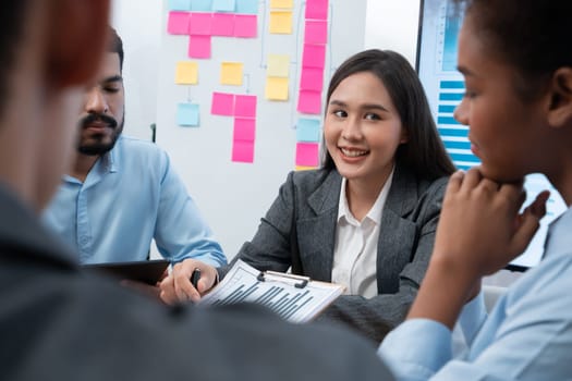 Multiracial analyst team use BI dashboard data to analyze financial report on meeting table. Group of diverse business people utilize data analysis by FIntech for business marketing decision. Concord