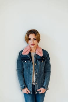 woman with a warm winter denim jacket stands on a white background