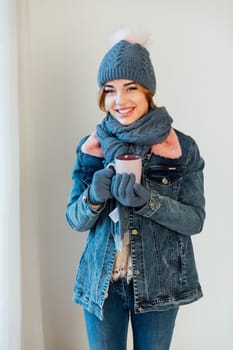 woman in warm winter clothes with a mug of mulled wine coffee tea