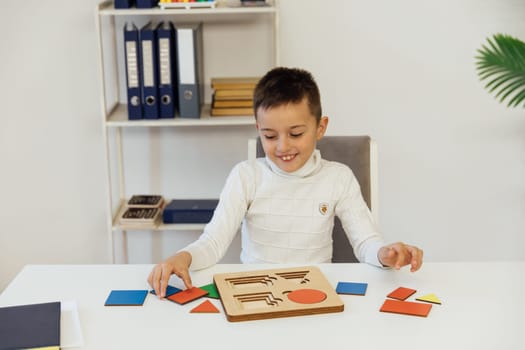 boy sits at the table with an educational game in the office