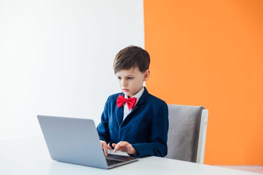 schoolboy boy sitting at a laptop at desk in a school in a classroom online education room