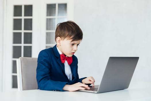 schoolboy boy sitting at a laptop at desk in a school in a classroom online education room