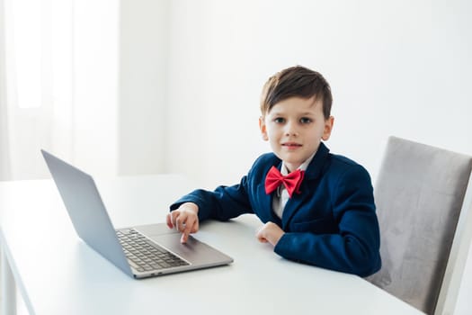 school student sitting at laptop at a desk in a classroom online education room