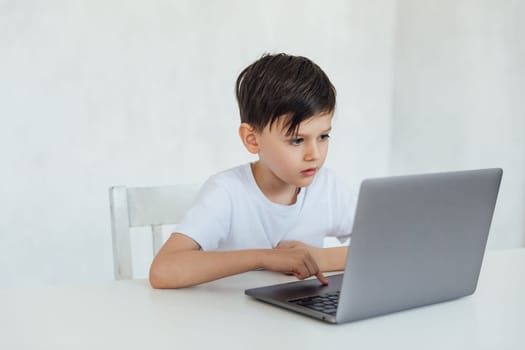 boy stares intently at laptop sitting at a desk in a classroom education online school