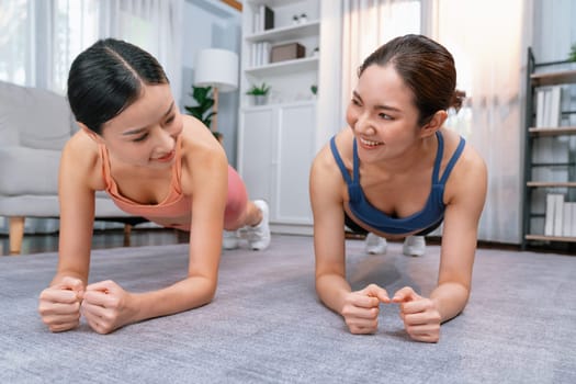 Fit young asian woman planing on the living room floor with her trainer or exercise buddy. Healthy lifestyle workout training routine at home. Balance and endurance exercising concept. Vigorous