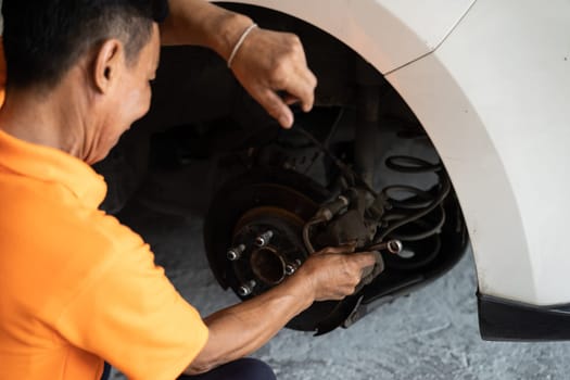 Hardworking mechanic changing car wheel in auto repair workshop. Automotive service worker changing leaking rubber tire in concept of professional car care and maintenance. Oxus