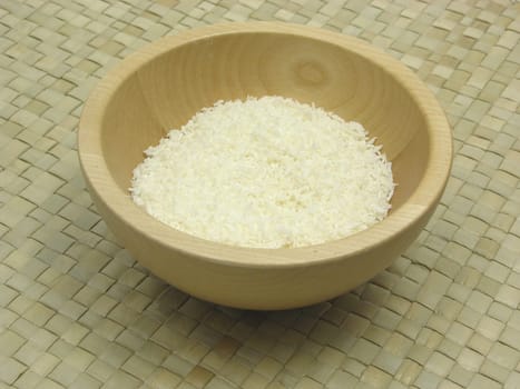 Wooden bowl with coconut flakes on rattan backing