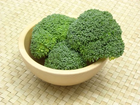 Wooden bowl with broccoli on rattan base