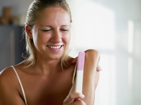 woman looking at pregnancy test and smiling. Copy space