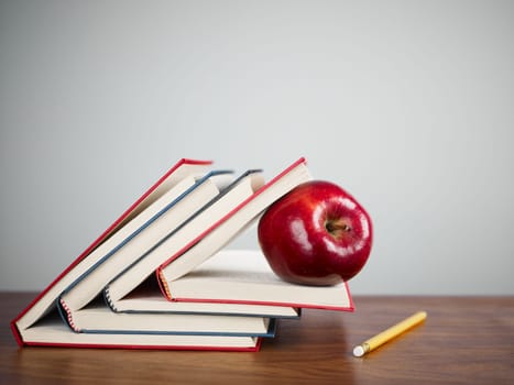 pile of books and red apple on desk. Copy space