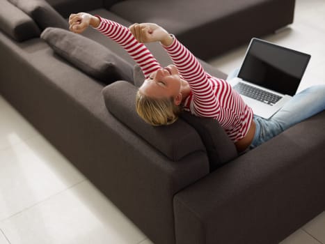 Woman stretching on sofa. High angle view, Copy space