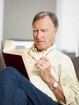 senior man reading book at home