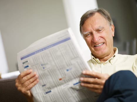 Senior man reading stock listings and smiling. Copy space