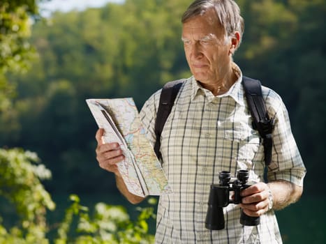senior hiker holding map and binoculars. Copy space