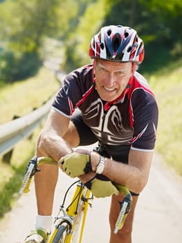 senior man leaning on road bike, looking at camera.