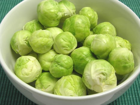 Brussels sprouts in white bowl and green placemat