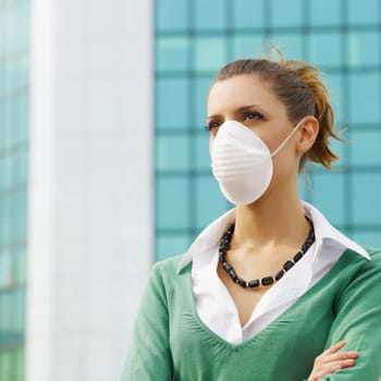 woman standing against office building and wearing protective mask. Copy space