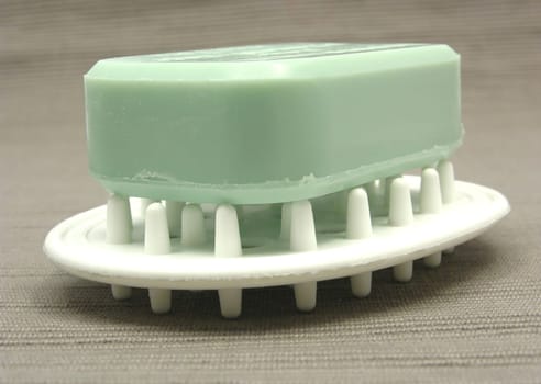 Green soap on soap tray against gray background