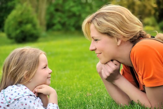 Young mother and daughter laying on the grass