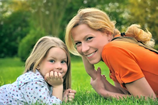 Young mother and daughter laying on the grass