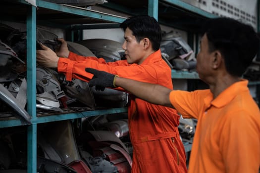 Mechanic worker inspect spare vehicle parts stored in inventory at automotive service. Reusing car components, optimizing resource and availability of spare part for repair and maintenance. Oxus