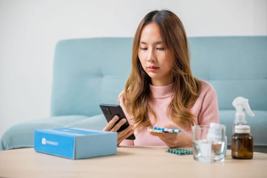 Sick female searching pills information and checking ingredient label and bottle of drug, Asian sick young woman reading medicine prescription on smart mobile phone, smartphone online pharmacy concept