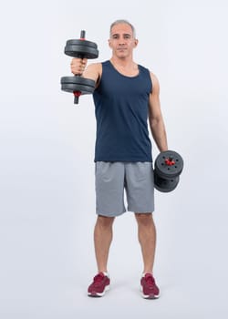 Full body length shot active and sporty senior man lifting dumbbell during weight training workout on isolated background. Healthy active physique and body care lifestyle for pensioner. Clout