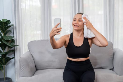 Active and sporty senior take selfie with smartphone after finishing home workout exercise. Healthy and fit body lifestyle for pensioner after retirement workout exercising at home. Clout