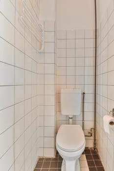 a white toilet in a small bathroom with tiled walls and black tiles on the floor, there is a mirror above it