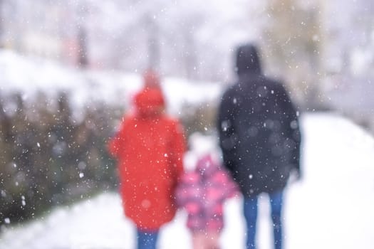 Back view portrait of happy family with child in winter park out of focus. High quality photo