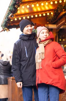 Young pair standing and smiling at Christmas market in Europe. High quality photo