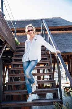 a woman in jeans stands on a wooden stairwell on the street