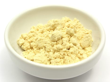 Soy flour in a small white bowl on a white background