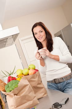 Young smiling woman with groceries in the kitchen