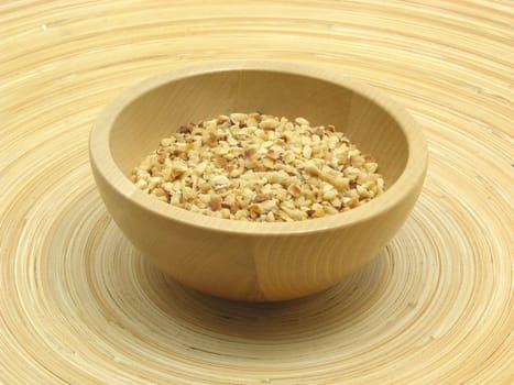 Wooden bowl with roasted hazelnuts on bamboo plate